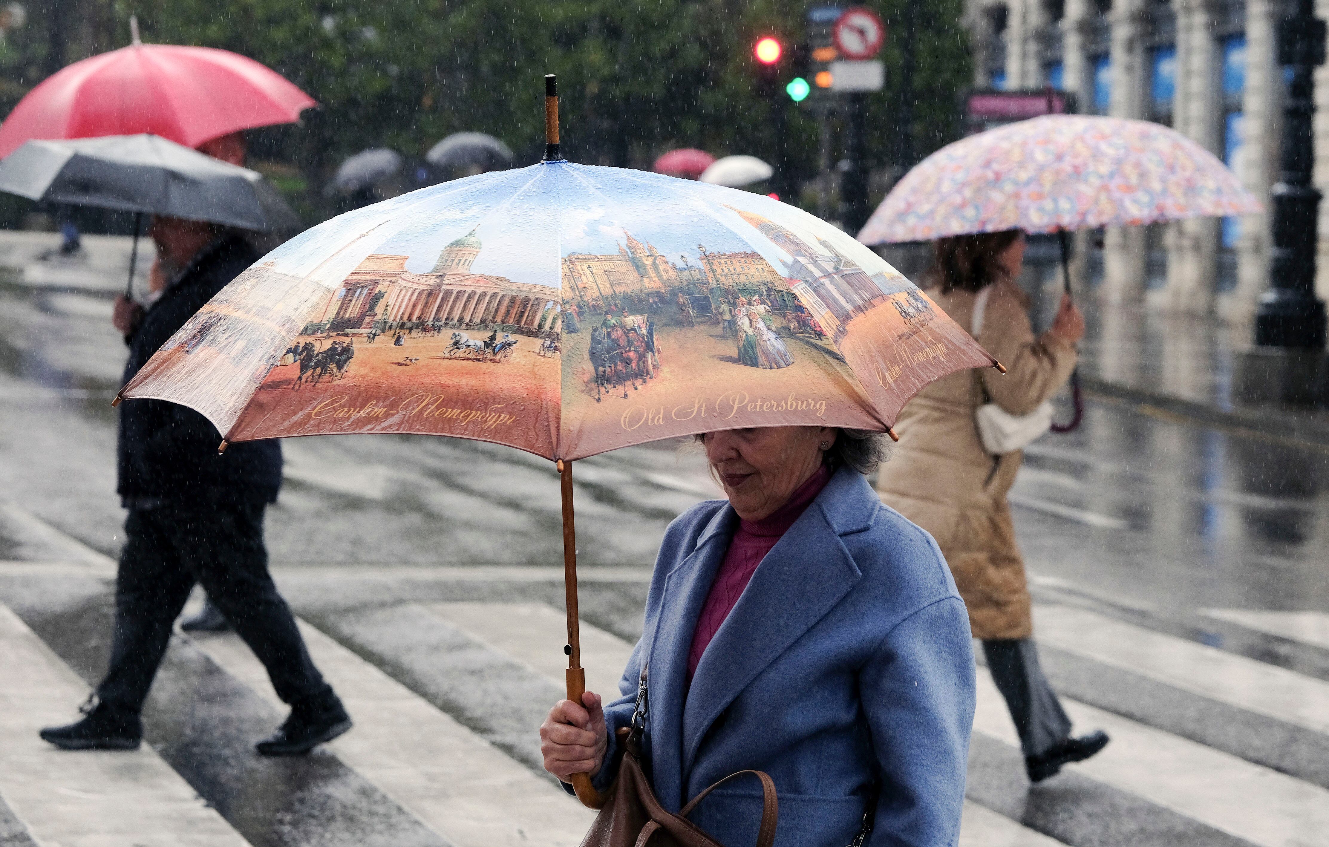 Una mujer se protege con un paraguas de la lluvia en Oviedo.