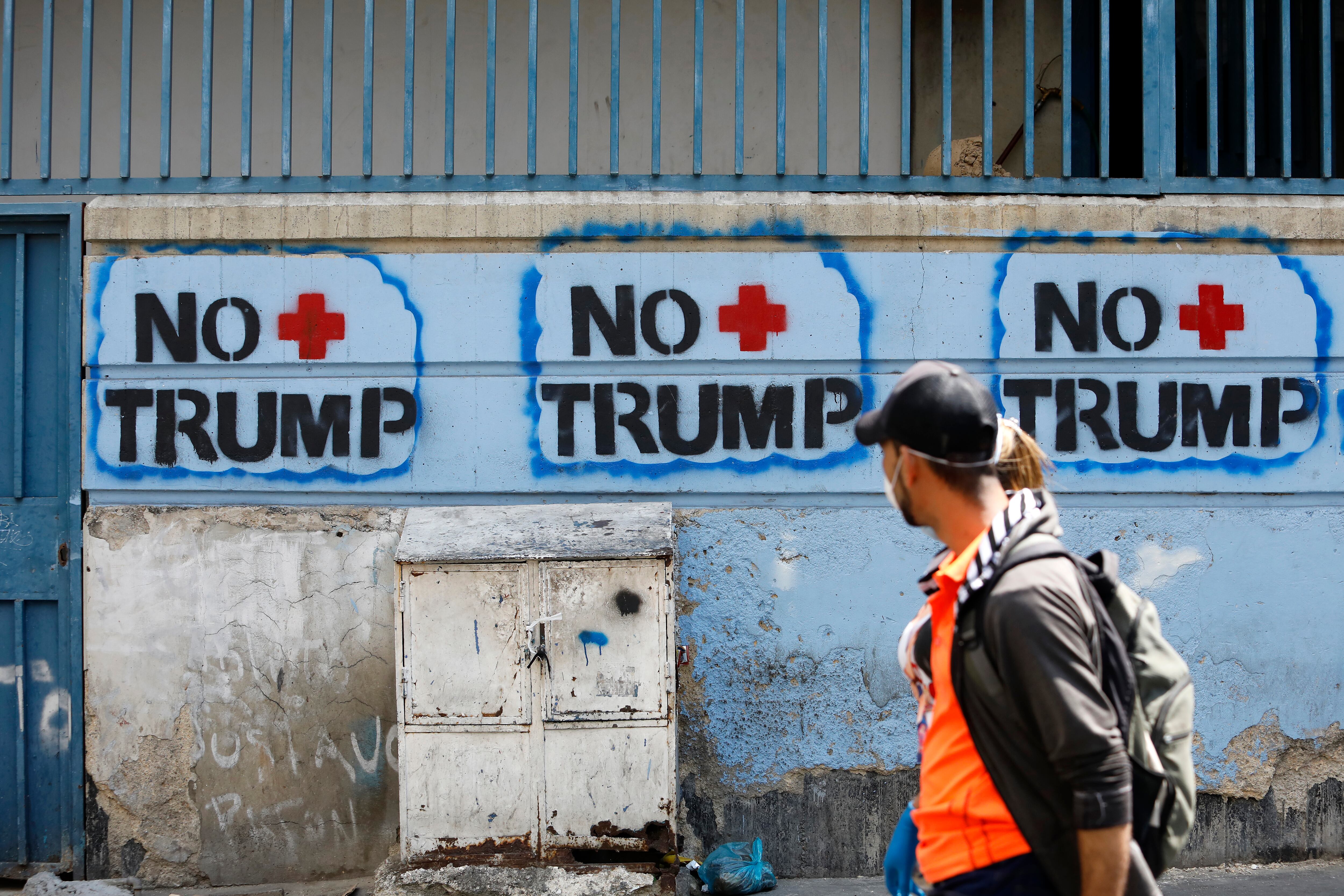 Una pareja pasa delante de unos graffitis contra Trump en Caracas