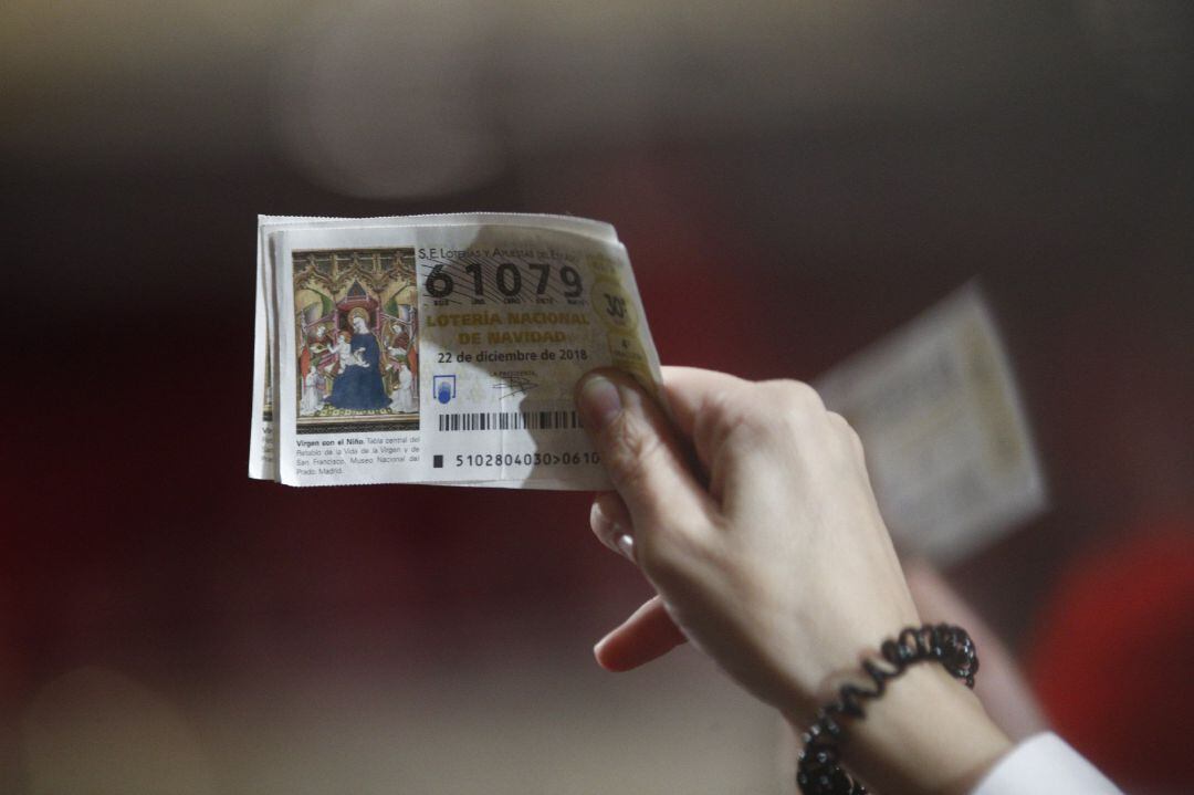 Una mujer agarra sus décimos antes de que comience el Sorteo Extraordinario de la Lotería de Navidad en el Teatro Real de Madrid