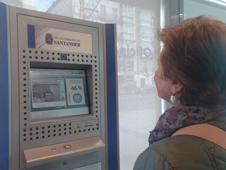 Una mujer mide el grado de su sonrisa en el dispositivo instalado en la oficina de turismo del Paseo Pereda