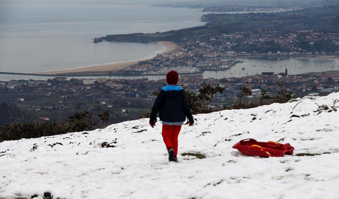 Un niño observa Hondarribia y Hendaia desde un monte Jaizkibel nevado esta semana.