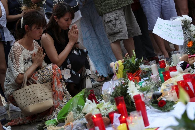 Women kneel as they pray at an impromptu memorial a day after a van crashed into pedestrians at Las Ramblas in Barcelona, Spain August 18, 2017. REUTERS Sergio Perez