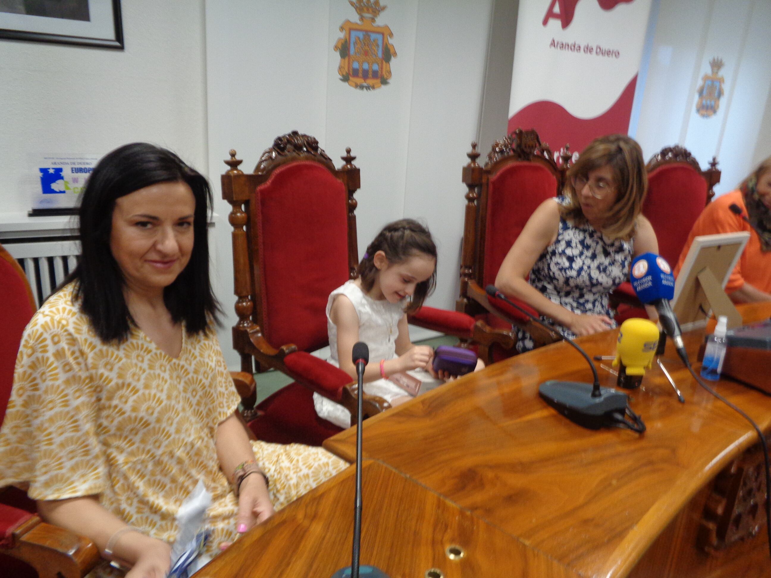 Ana abre impaciente su regalo entre la alcaldesa y su madre