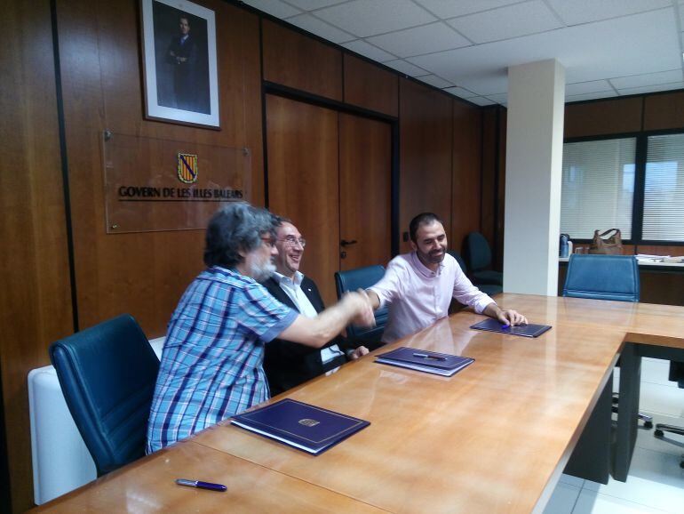 Cruce de manos entre Biel Caldentey (STEI) y Toni Baos (CCOO) con el conseller de Educación, Martí March, después del acuerdo firmado.