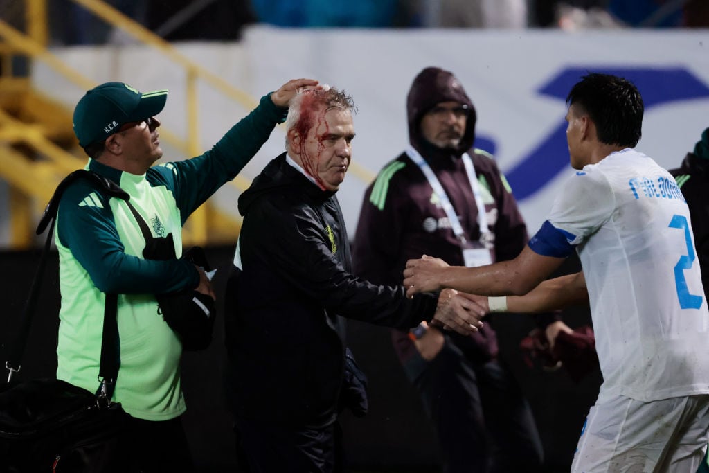 Javier Aguirre siendo trasladado al túnel de vestuarios tras recibir el impacto de una lata desde la grada