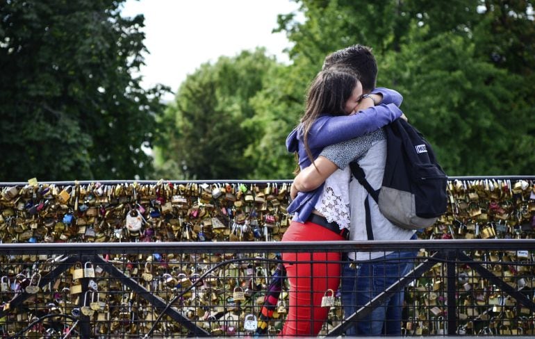 Una pareja se abraza en el Puente Nuevo de París repleto de candados.