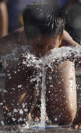 Un niño juega con agua en Concepción, al sur de Santiago (Chile)