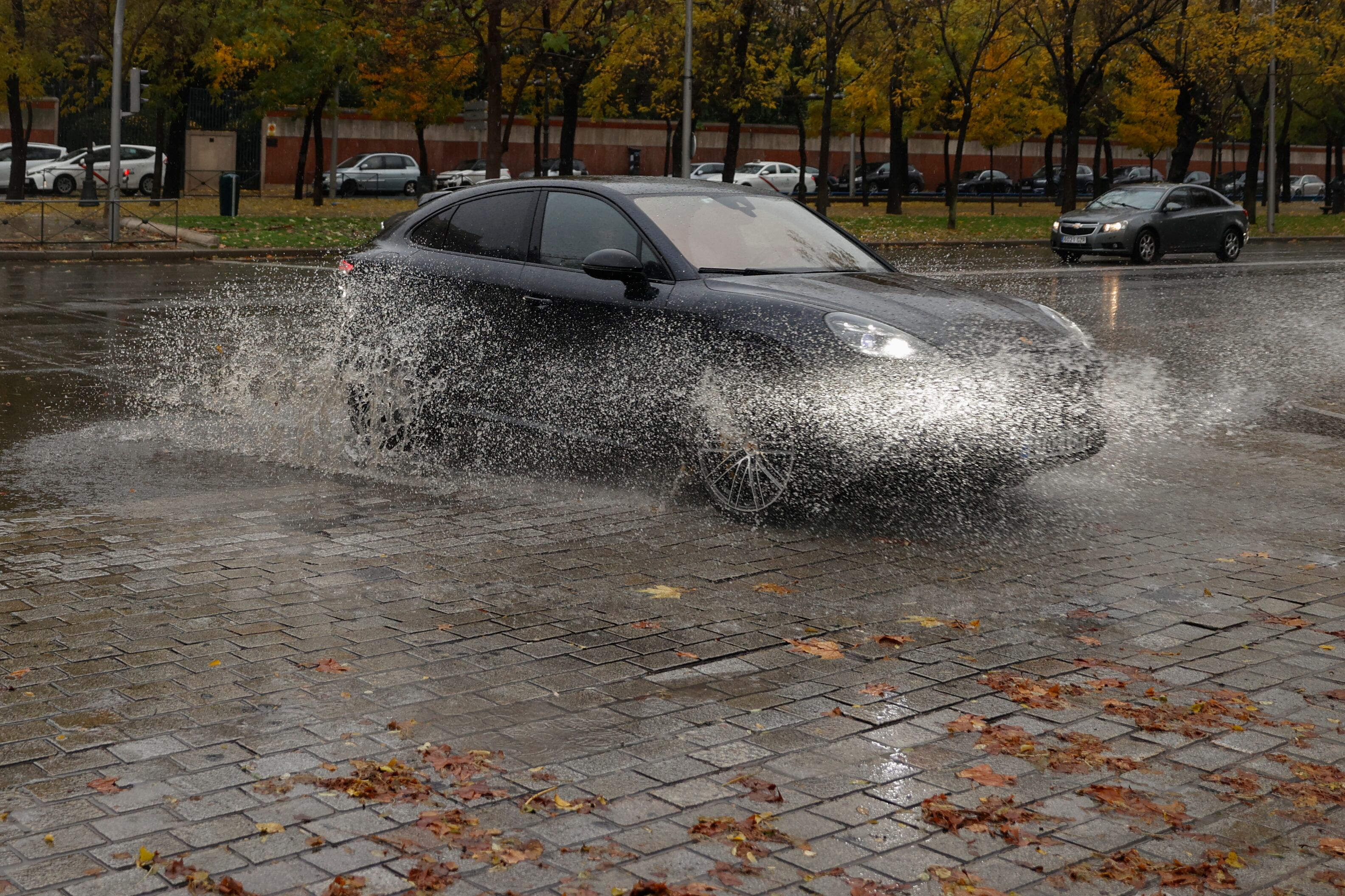 MADRID, 13/12/2022.- Un coche salpica a su paso por una calle encharcada este martes en Madrid capital. 