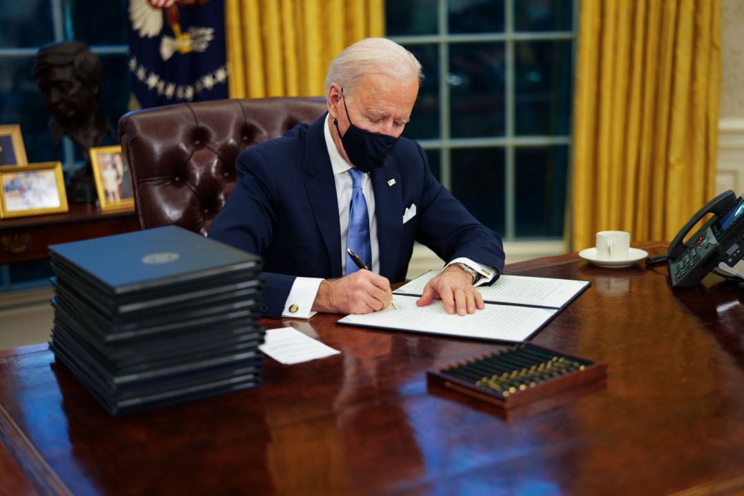 Joe Biden firma un decreto en el Despacho Oval.