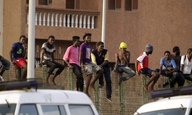 Alrededor de treinta inmigrantes de origen subsahariano, encaramados en la parte alta de la valla de Melilla, después de haber protagonizado un nuevo intento de entrada masivo por el perímetro fronterizo