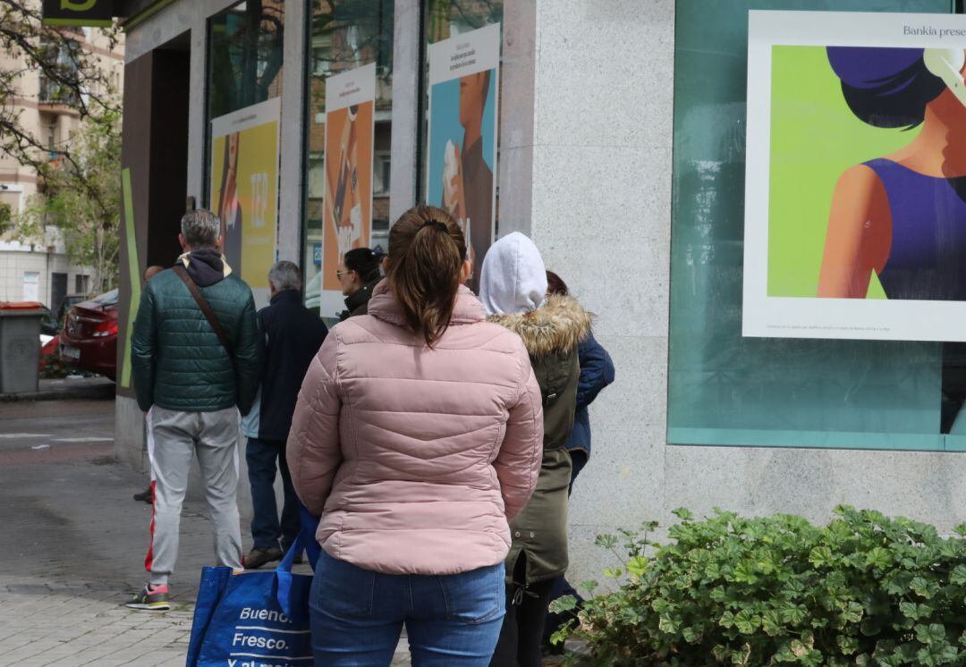 Personas en fila guardan su turno para entrar en una oficina bancaria