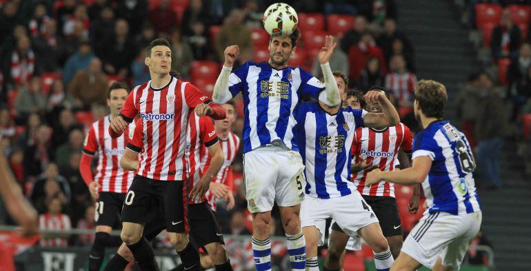 GRA501. BILBAO, 28/04/2015.- El centrocampista de Real Sociedad Markel Bergara (c) cabecea el balón junto al delantero Aritz Aduriz, del Athletic de Bilbao, durante el encuentro correspondiente a la jornada 34 de Primera División que se disputa esta noche en el estadio de San Mamés. EFE/Luis Tejido.