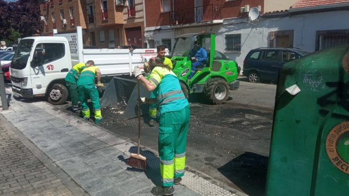 Operarios limpiando una zona de contenedores incendiada