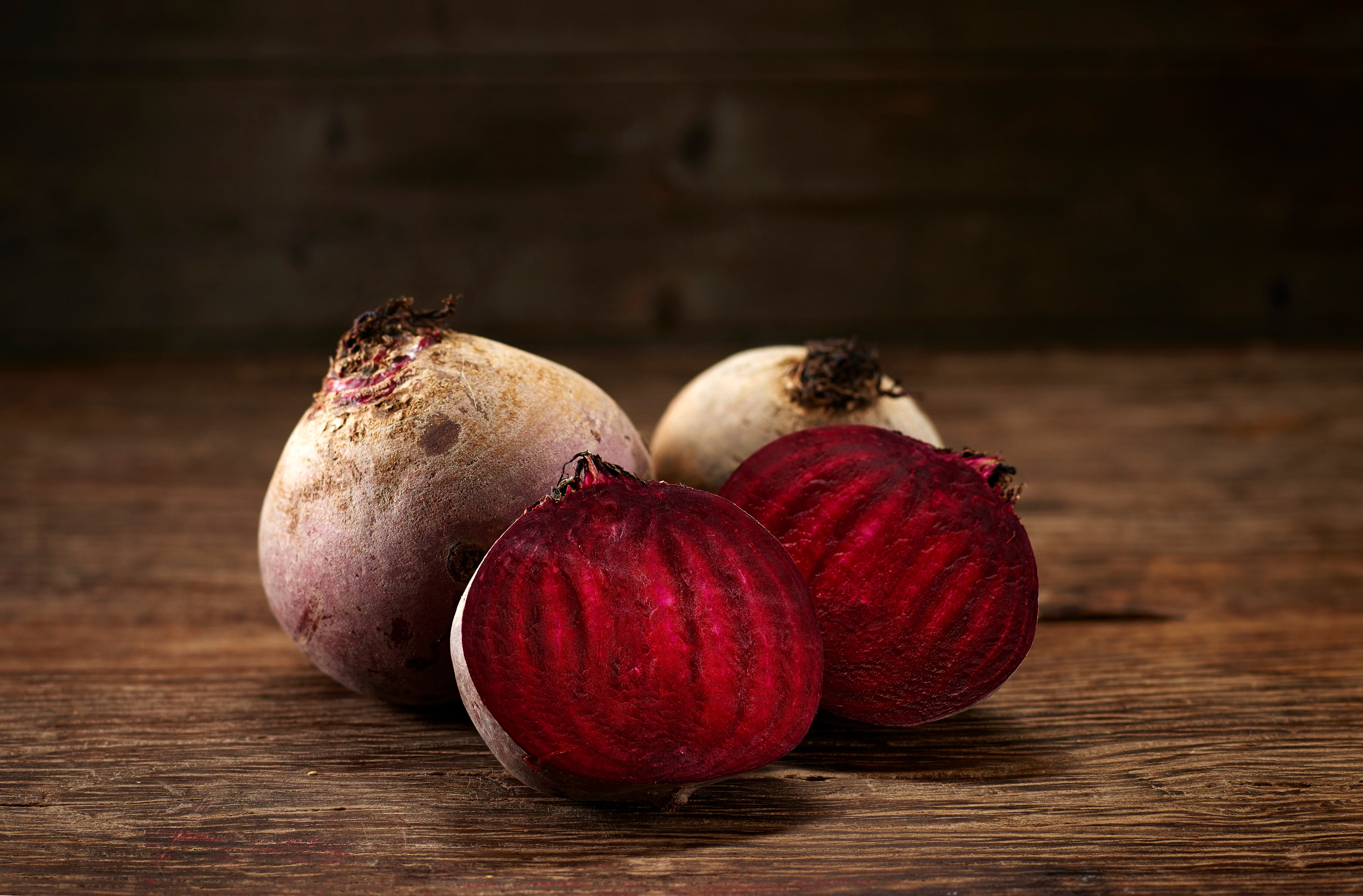 Whole and sliced beetroot on dark wood, copy space