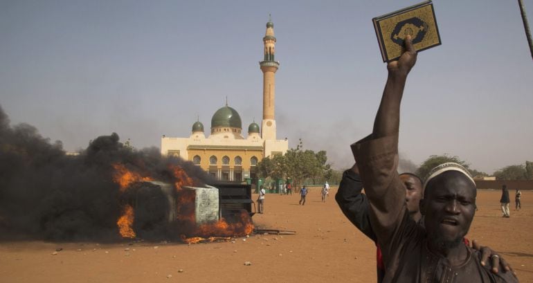 A man holds a copy of the Koran during a protest against Niger President Mahamadou Issoufou&#039;s attendance last week at a Paris rally in support of French satirical weekly Charlie Hebdo, which featured a cartoon of the Prophet Mohammad as the cover of its f