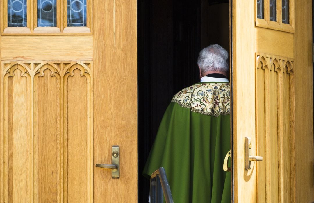 Un cura accede al interior de una iglesia.