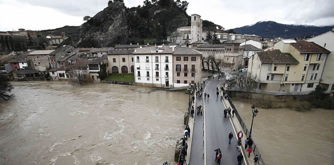 Un grupo de personas observan el rio Ega que sufría un fuerte crecimiento, desbordándose en algunos puntos, aunque de momento no ha invadido el casco viejo de la localidad de Estella (Navarra).