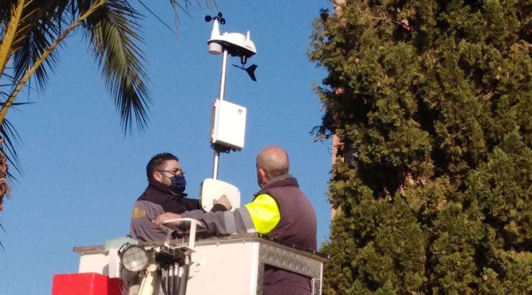 Dos operarios instalan una estación medidora de la calidad del aire