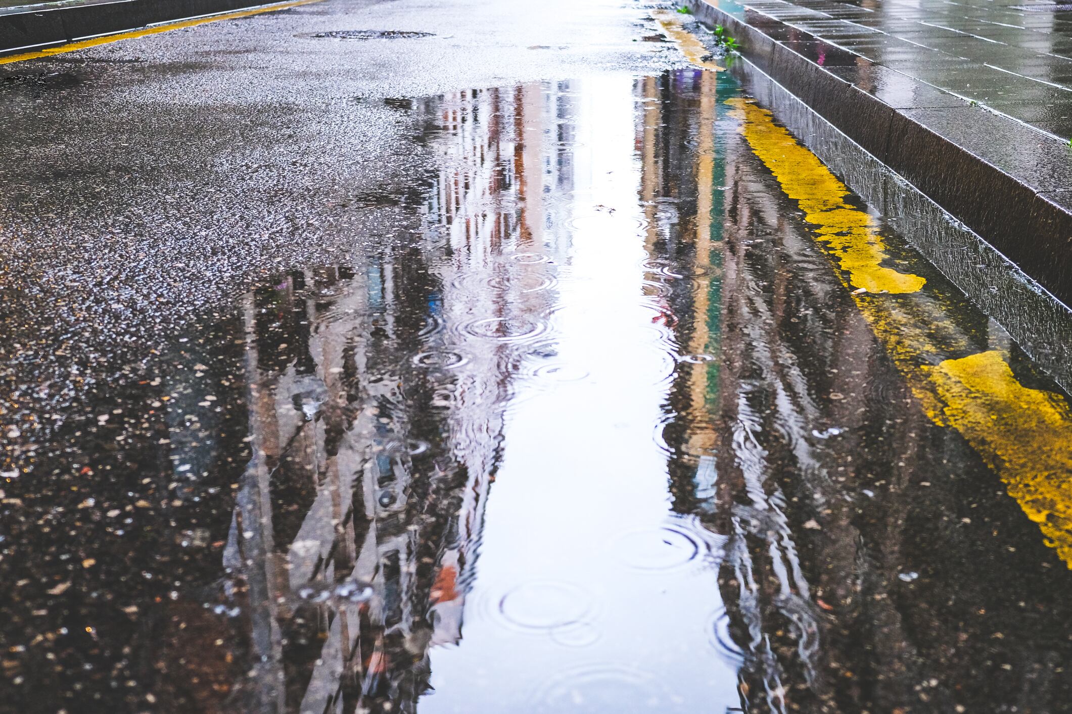 Charcos de lluvia se acumulan en el asfalto de una calle