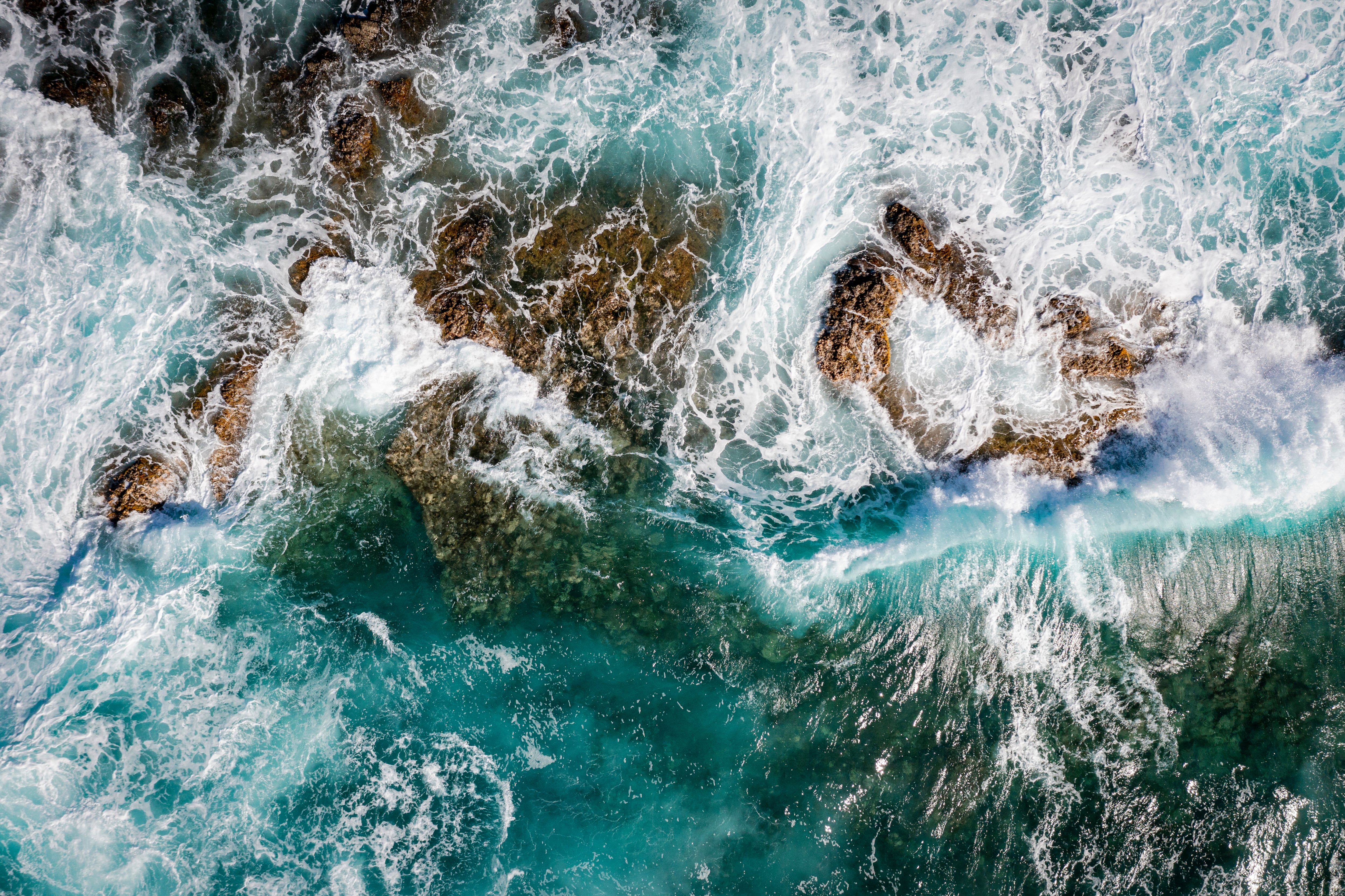 Aerial view of vortex created by waves of the rough ocean crashing on rocks