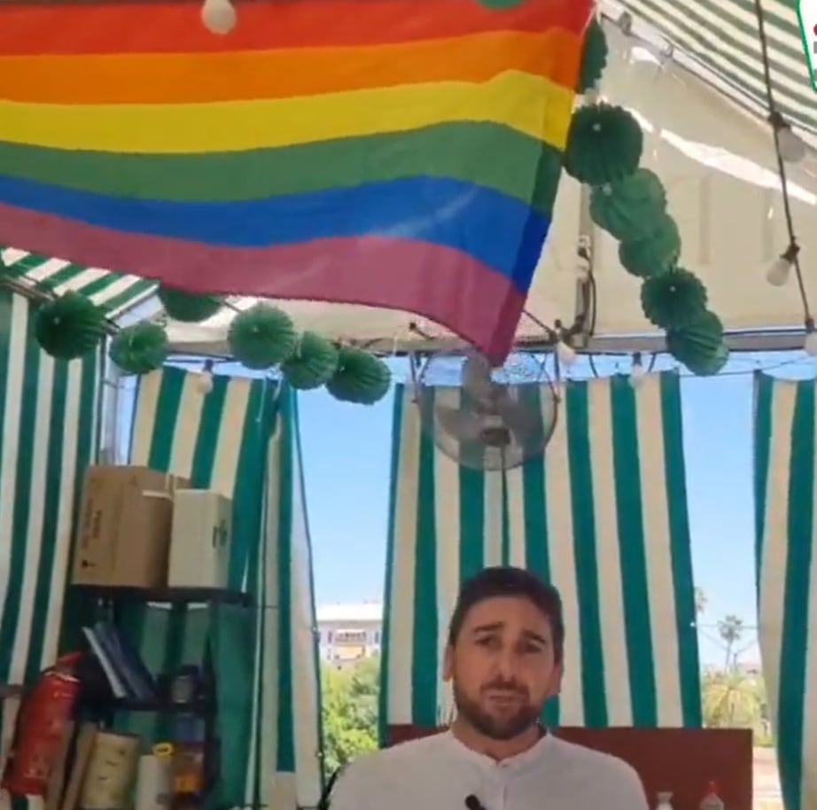 Ismael Sánchez, concejal de IU, junto con la bandera LGTBI en la caseta del partido