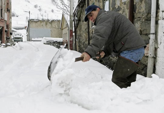 Un hombre retira nieve en Pajares (Asturias)