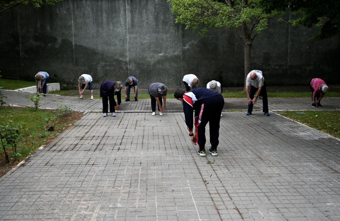 Archivo - Un grupo de ancianos realiza ejercicio en el jardín de un centro de día de personas mayores.