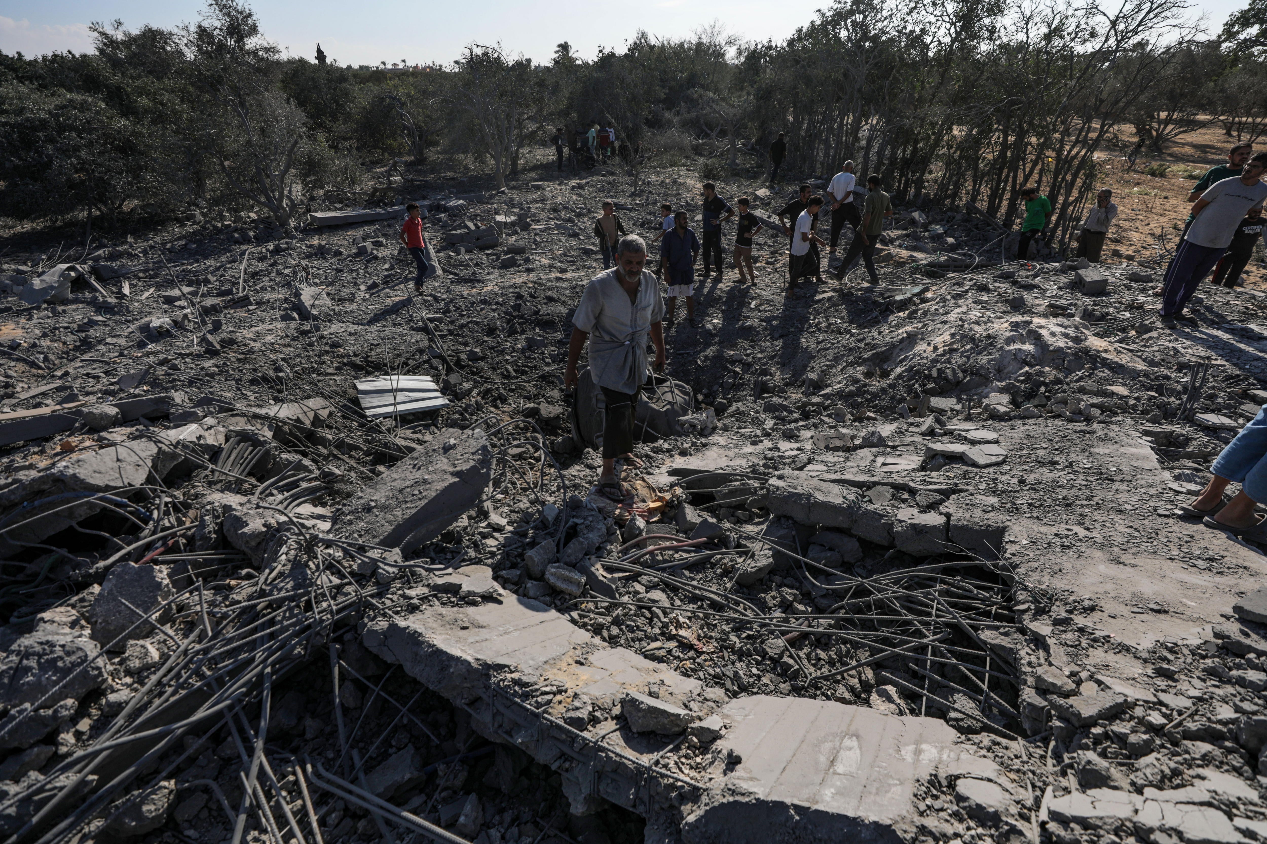 Palestinos buscan entre los escombros de una casa destruida tras los ataques aéreos israelíes en el campo de refugiados de Al-Maghazi, Gaza