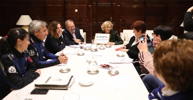 Manuela Carmena, mostrando las firmas, junto a las representantes de No Acepto, los concejales de Seguridad y Política de Género y Diversidad y varios agentes de policía. 