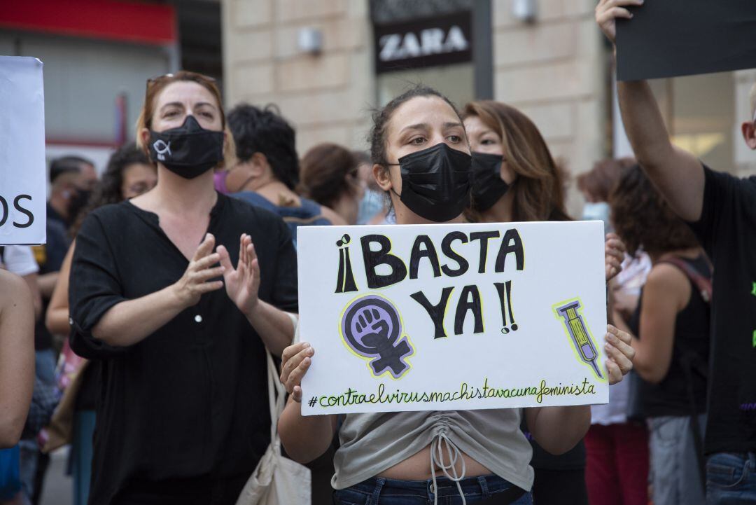 Una mujer con un cartel en el que se lee: `Basta ya´, participa en una concentración feminista.