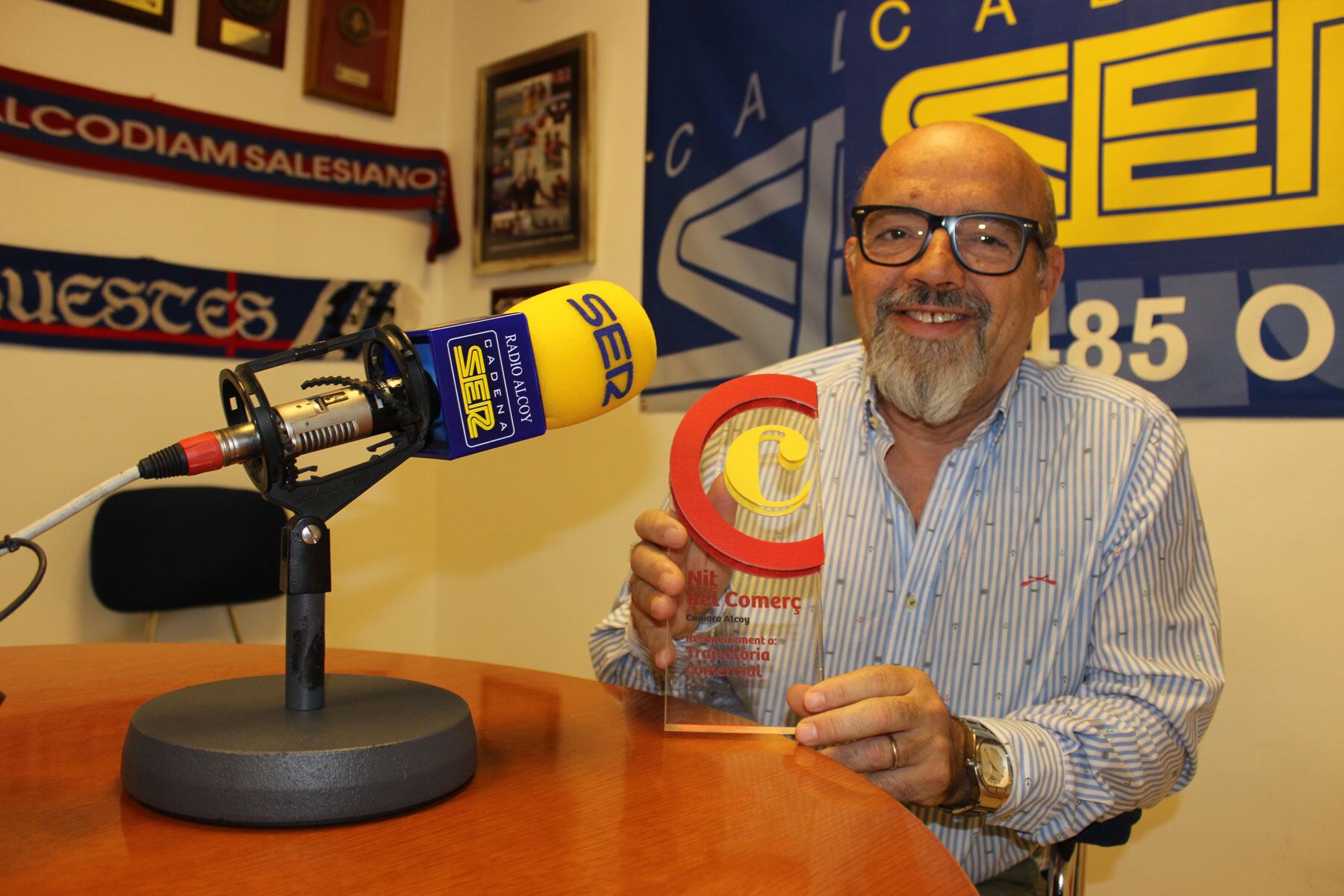 Jordi Juliá en el estudio de Radio Alcoy mostrando el trofeo recibido por la Cámara de Comercio por su trayectoria comercial