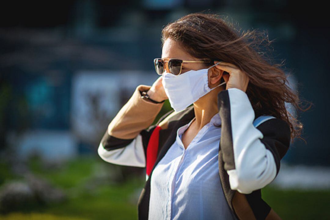 Mujer poniéndose la mascarilla en la calle 