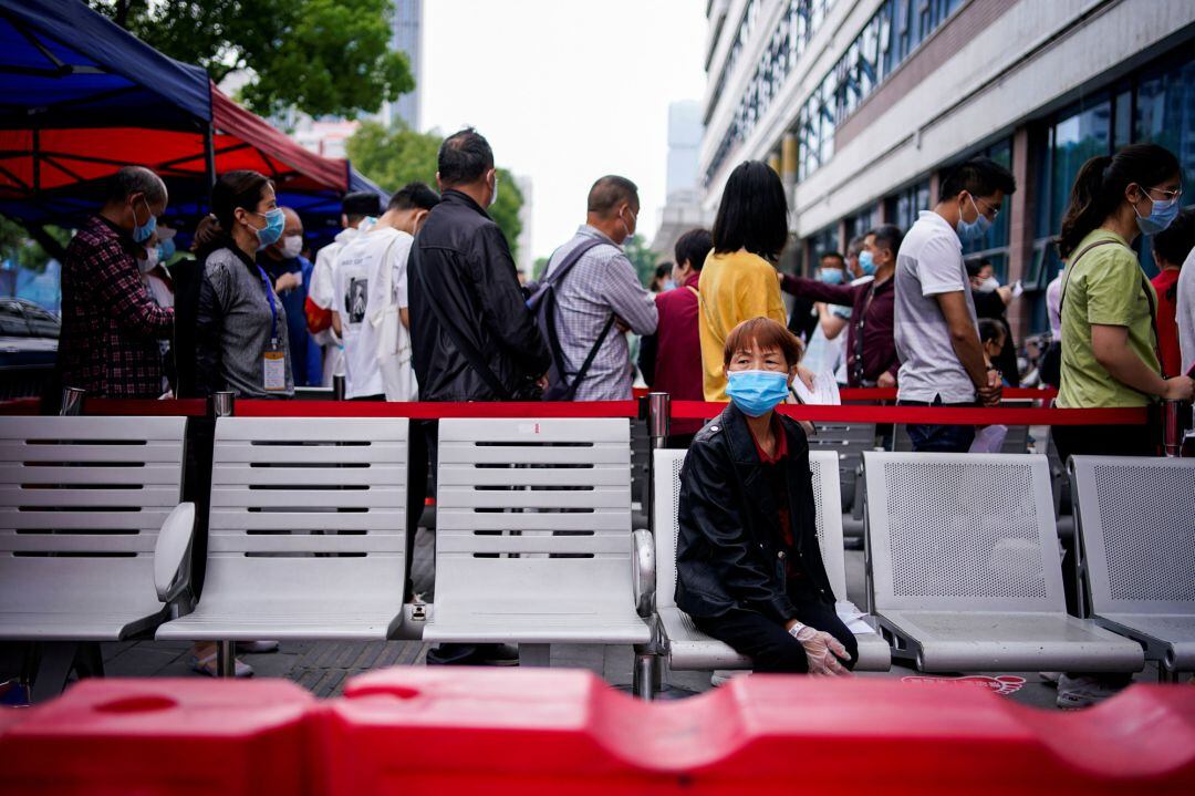 Una mujer espera sentada a las colas para pasar el test del coronavirus en Wuhan