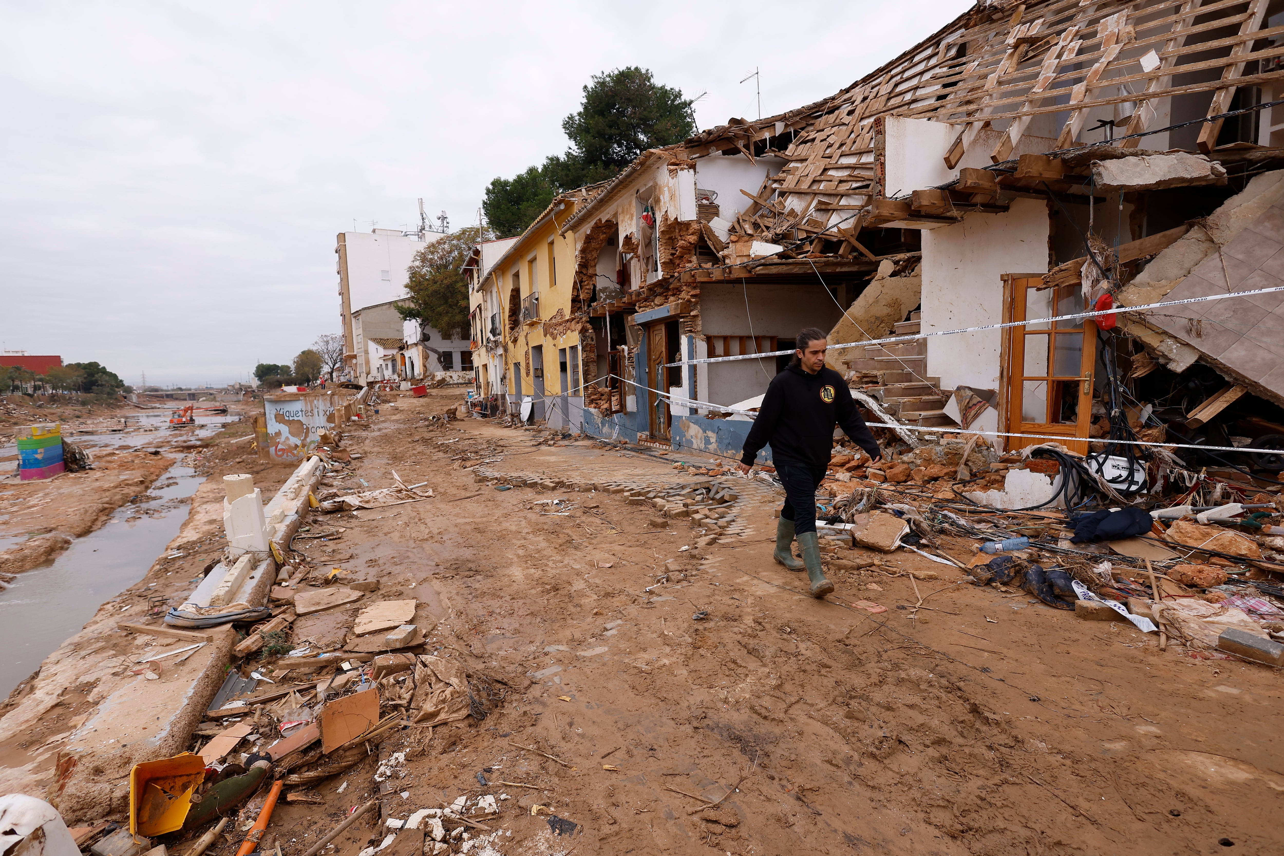 Un vecino pasa junto al Barranco del Poyo, delante de las casas destrozadas por las DANA del 29 de octubre.