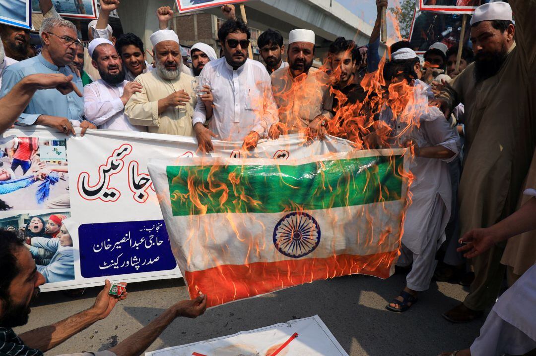 Manifestantes pakistaníes protestan en Peshawar contra la decisión de India quemando su bandera.