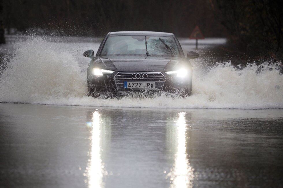 Un coche cruza una carretera  inundada