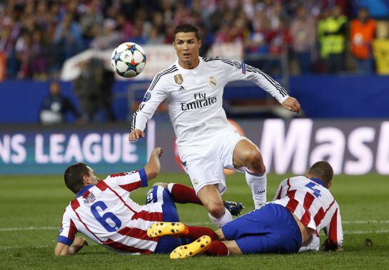 Cristiano Ronaldo (c) escapa entre Koke (i) y Suárez, del Atlético de Madrid, durante el partido Liga de Campeones