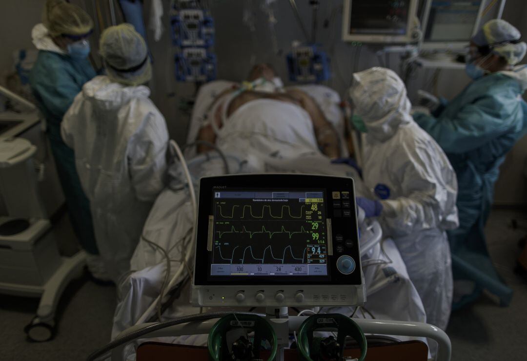 Personal sanitario totalmente protegido atiende a un paciente ingresado en la Unidad de Cuidados Intensivos.