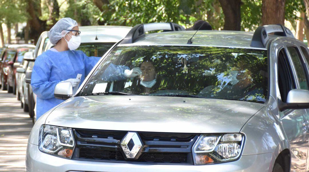 Una enfermera realiza una PCR a una mujer en un coche.