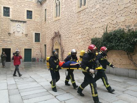 Varios bomberos evacúan a uno de los heridos durante el simulacro de incendio del Alcázar