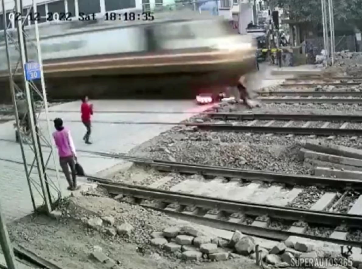 Un motorista se salva de ser atropellado por un tren en la India.