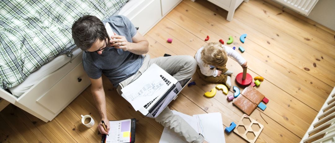 Padre trabajando en casa mientras su hijo juega