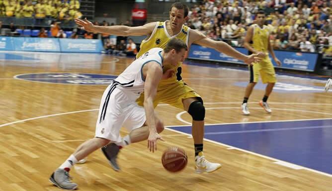 El escolta lituano del Real Madrid Martynas Pocius ataca frente a la oposición del alero estadounidense Levi Rost, del CB Canarias