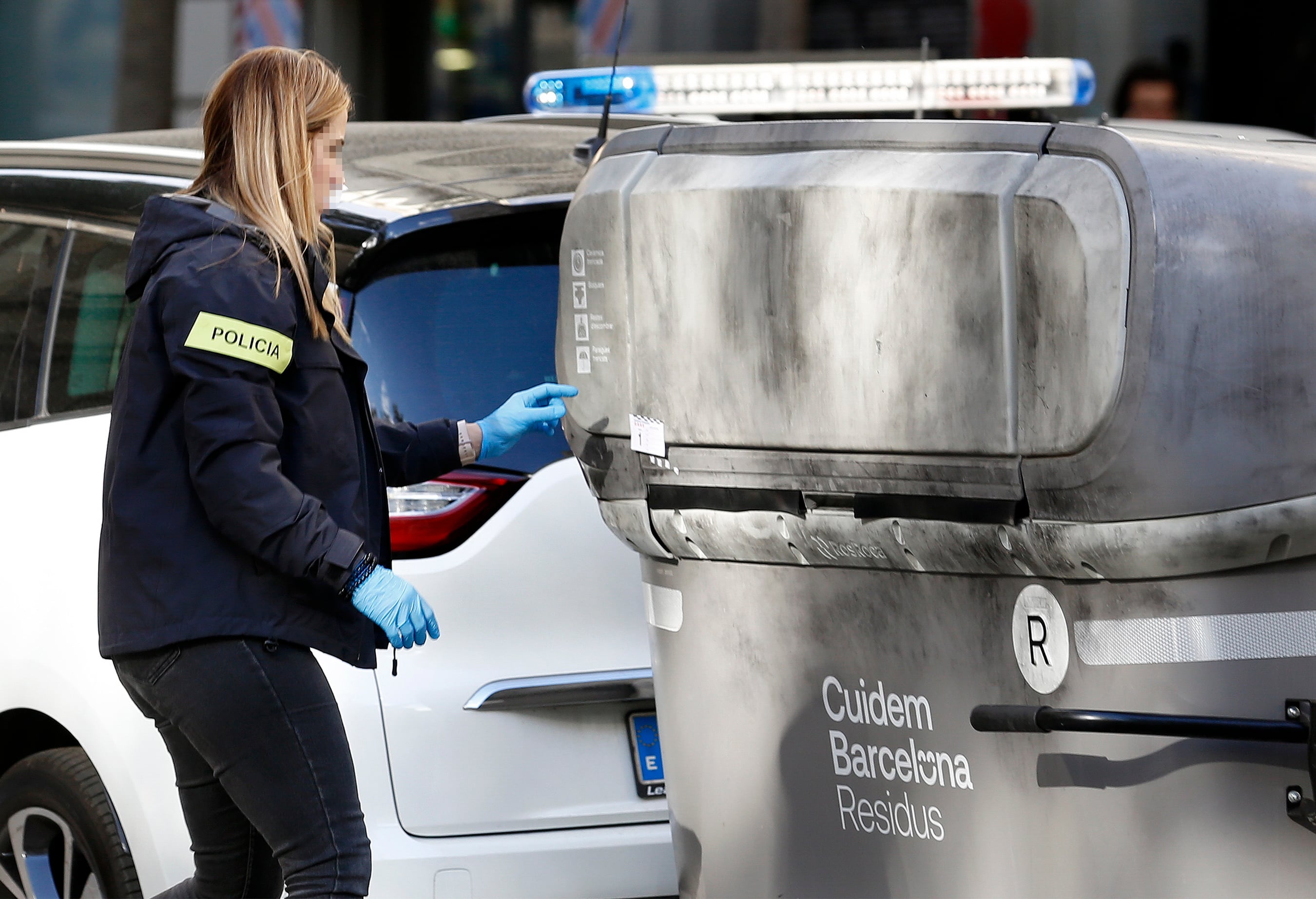 Una agente de los Mossos d&#039;Esquadra realiza su trabajo en la calle Casanova con Avenida de Roma este martes en que un vecino ha hallado el cadáver mutilado de una persona dentro de una maleta en un contenedor (i) del bario de L&#039;Eixample de Barcelona, ante lo que la policía catalana ha abierto una investigación