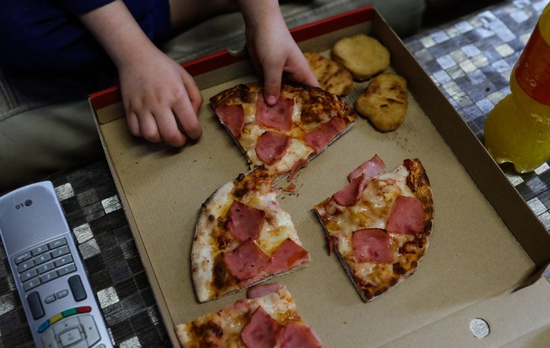 Un niño come pizza del menú infantil de Telepizza.