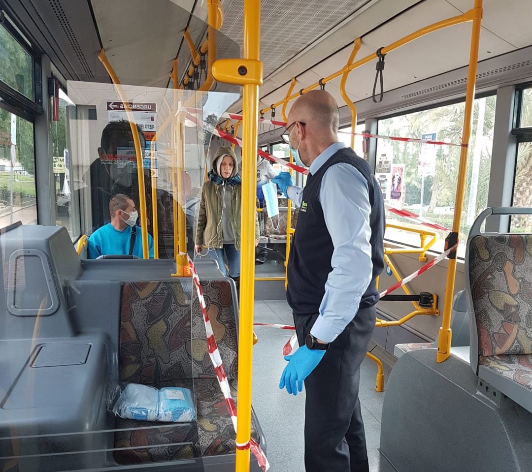 Un conductor del servicio urbano de bus entrega mascarillas a los viajeros