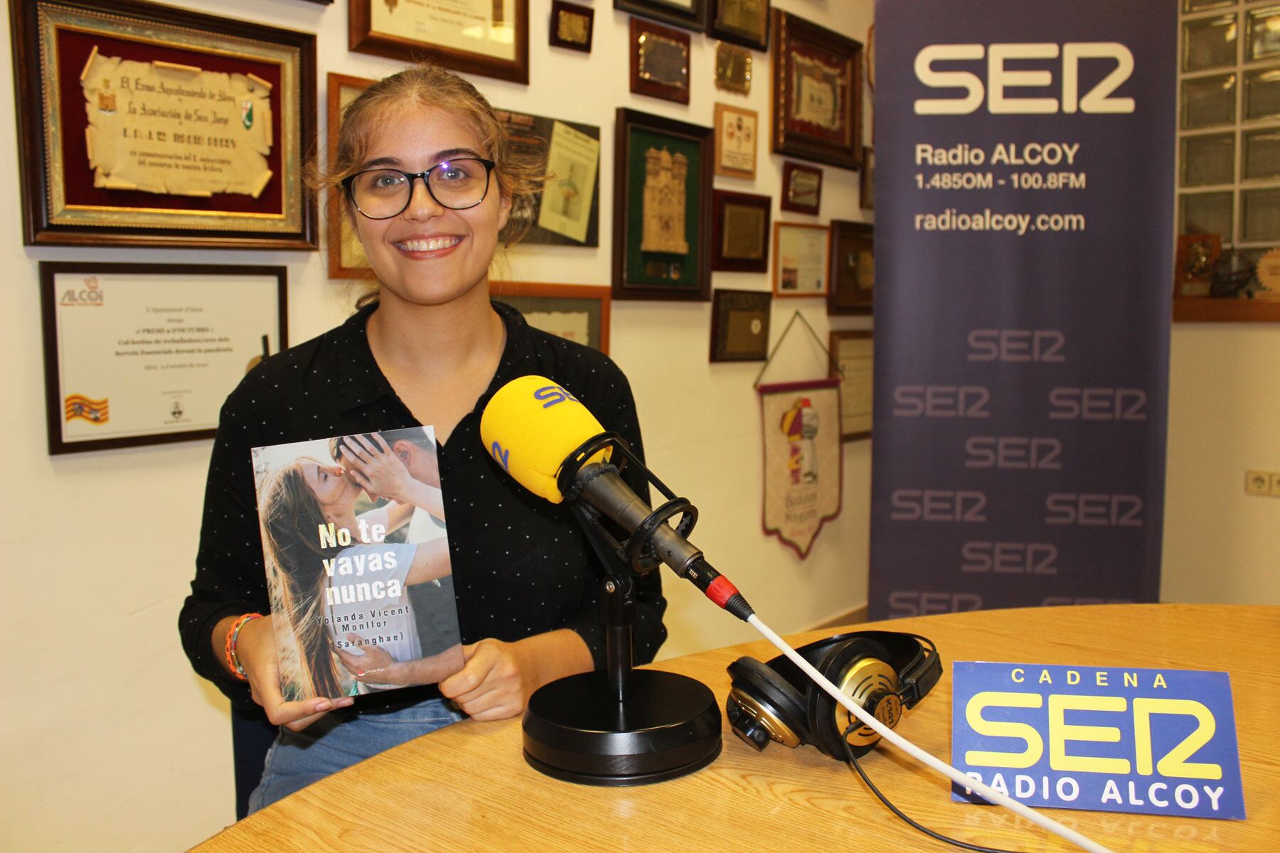 Yolanda Vicent, en el estudio central de Radio Alcoy, con un ejemplar de su tercer libro 'No te vayas nunca'
