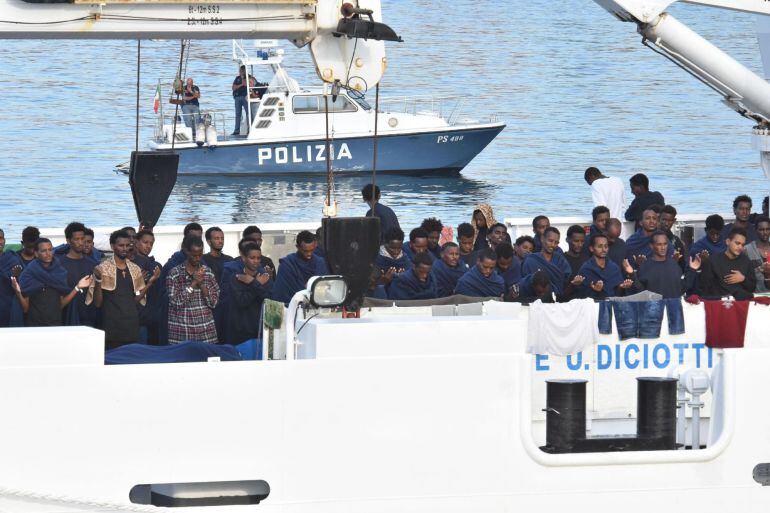 Migrantes rezan a la espera del desembarco del barco italiano de la Guardia Costera italiana en Catania, Italia.