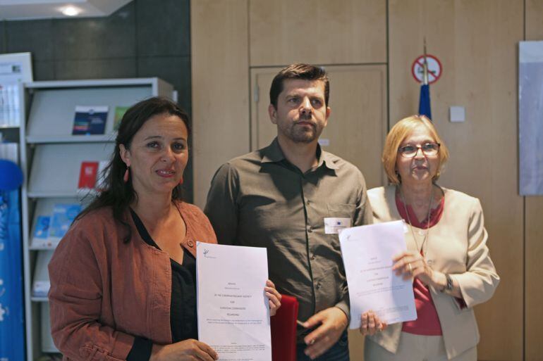 La eurodiputada y portavoz del Bloque Nacionalista Gallego en Europa, Ana María Miranda (i), junto al presidente de la Asociación de Víctimas del Alvia 04155, Jesús Domínguez (i), y la vocal de la asociación, Teresa Gómez (d), muestran el informe sobre el