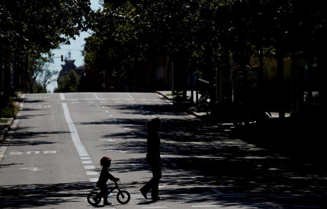 Un niño en bicicleta acompaña a su madre en una calle de Barcelona.